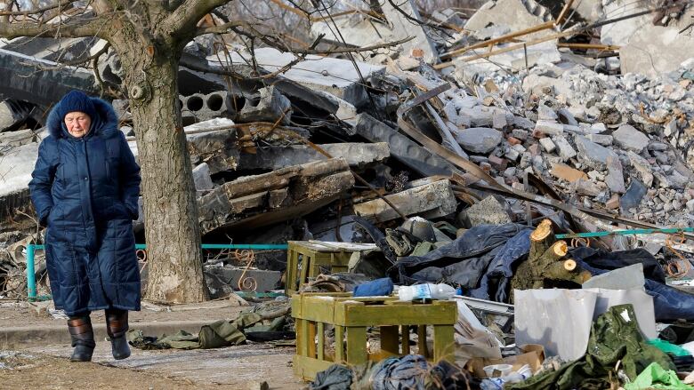 A woman walks near the ruin of a vocational college which Russia says was housing soldiers when it was struck by HIMARS rockets on New Years day. 