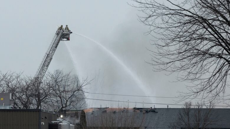 Firefighters on ladder seen trying to put out a fire at a hazardous waste management company in St. Catharines, Ont.