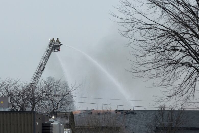 Firefighters on ladder seen trying to put out a fire at a hazardous waste management company in St. Catharines, Ont.