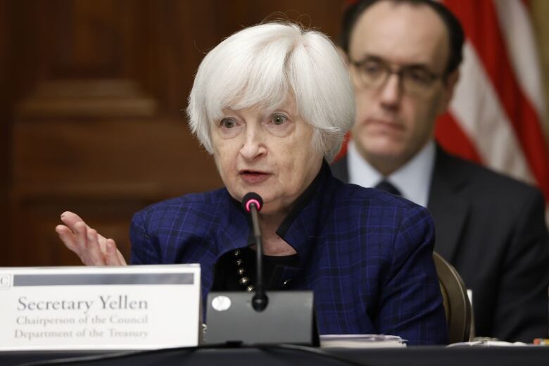 Janet Yellen, US Treasury secretary, speaks into a microphone in front of a sign with her name on it.