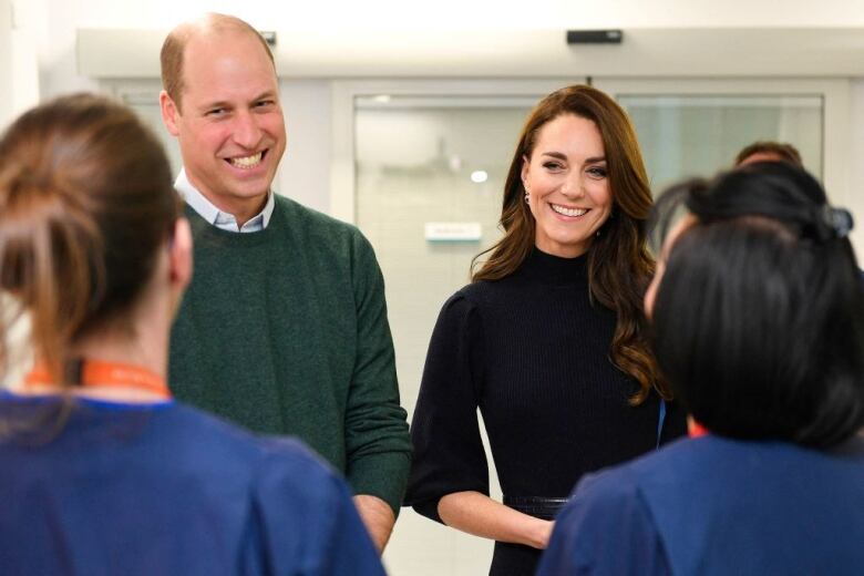 Two people talk with two members of a hospital staff.