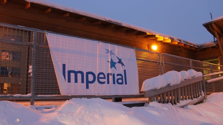 A white Imperial Oil banner hangs on a railing outside of a snow covered building.