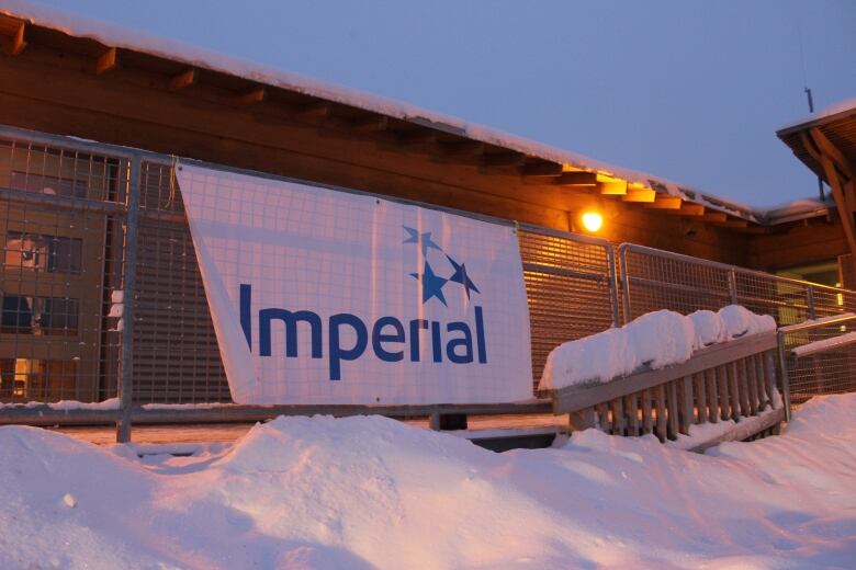 A white Imperial Oil banner hangs on a railing outside of a snow covered building.