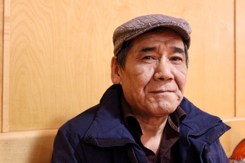 Headshot of a man in a blue jacket and a golf cap.