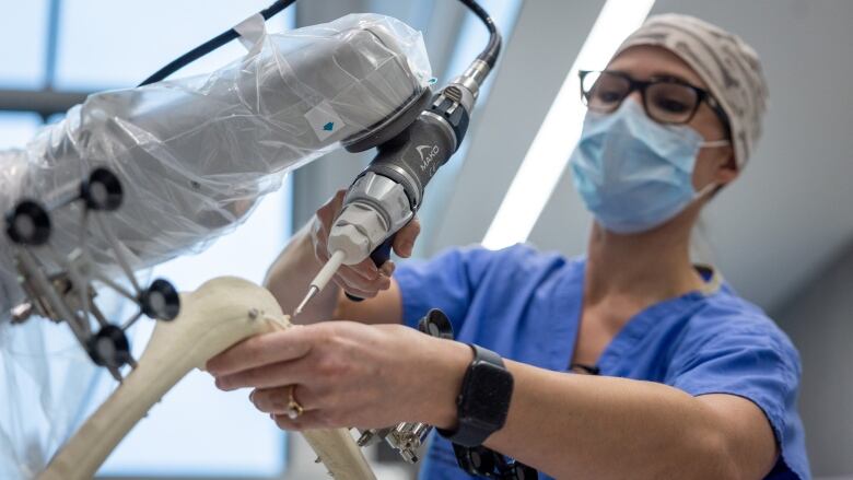 A surgeon drills into a practice hip bone using a robotic assistant. 