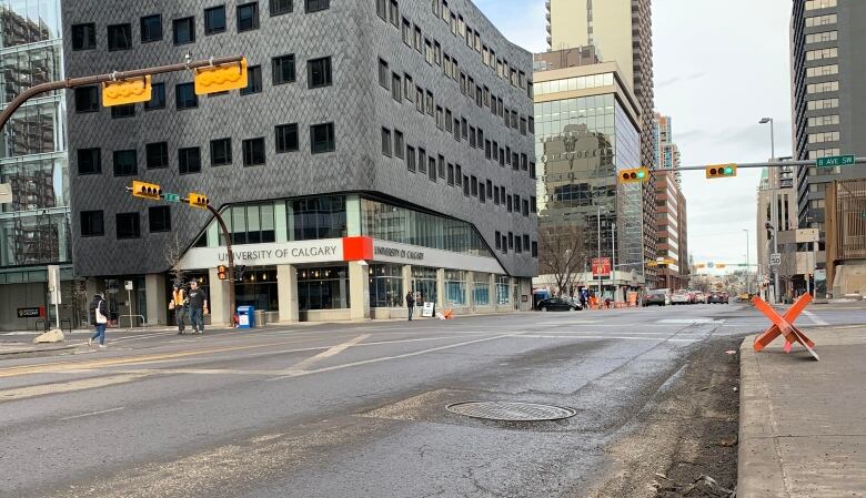 an empty stretch of road where two streets intersect. Tall buildings can be seen in the background 