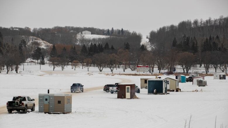 Ice fishing shacks sit on a frozen lake.