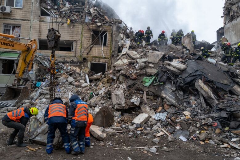 Emergency workers at a destroyed apartment building.