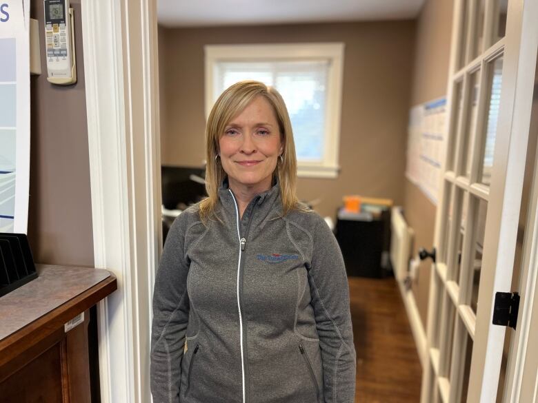 A woman stands in an office smiling at the camera. 