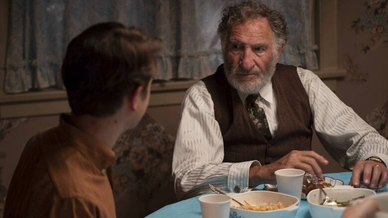 Judd Hirsch sits at a table in character in a scene from Steven Spielberg's autobiographical film The Fabelmans.