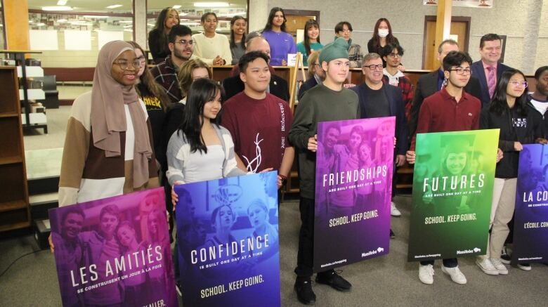 Students stand with multi-coloured posters.