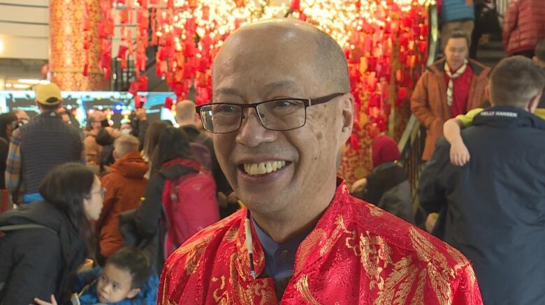 A man wearing a traditional red outfit smiles at the camera