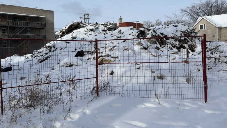 A pile of rubble can be seen behind a construction fence.