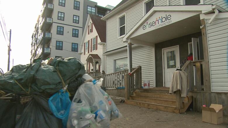 exterior of building with shopping cart piled with cans, bottles and covered in a green tarp