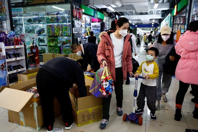 A mother and child walk through a mall in Bejing, past toys.