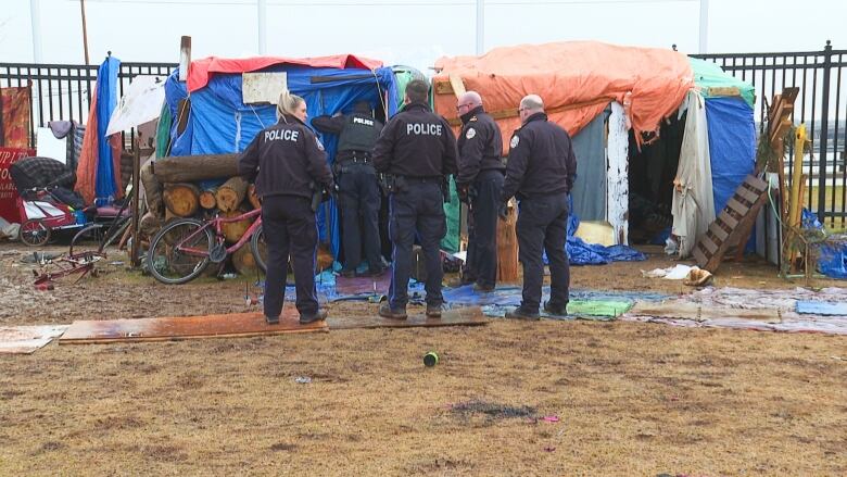 Police and fire officials inspect the encampment after a fire broke out early Tuesday morning.