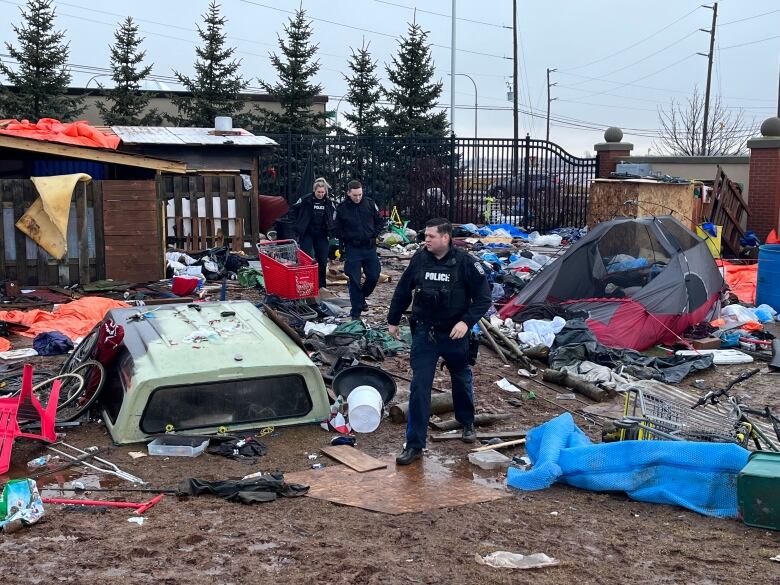 Police walk through the debris at the encampment.