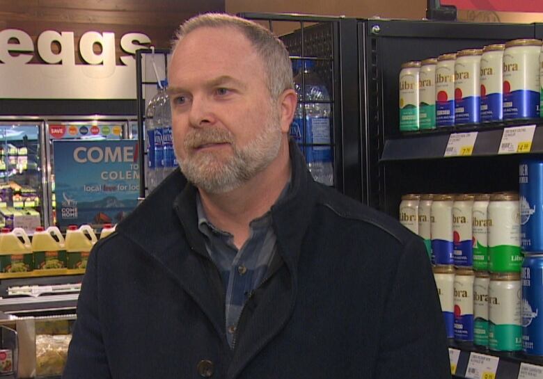 A man stands in the aisle of the grocery store.