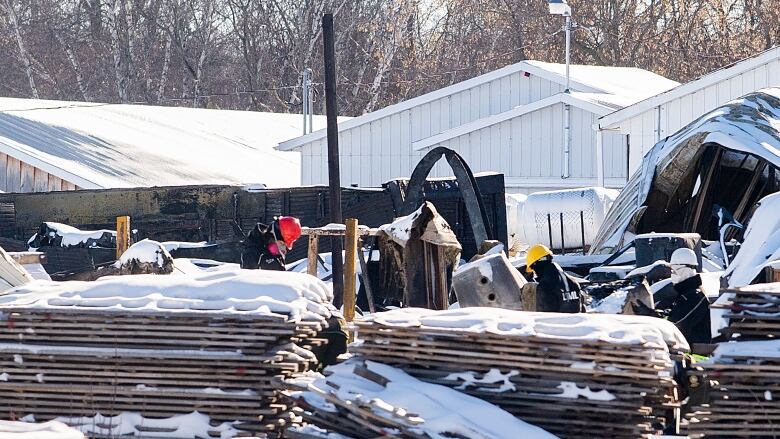 People in hardhats inspecting piles of debris covered in snow