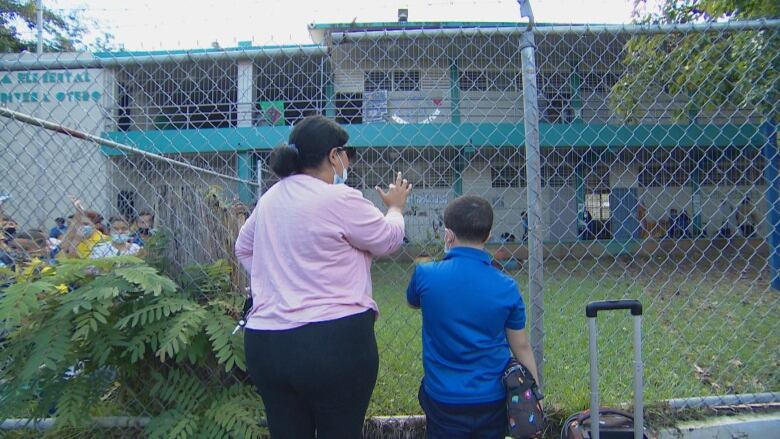 An adult and her a child wait outside Escuela Rafael Rivera Otero in San Juan, Puerto Rico. 