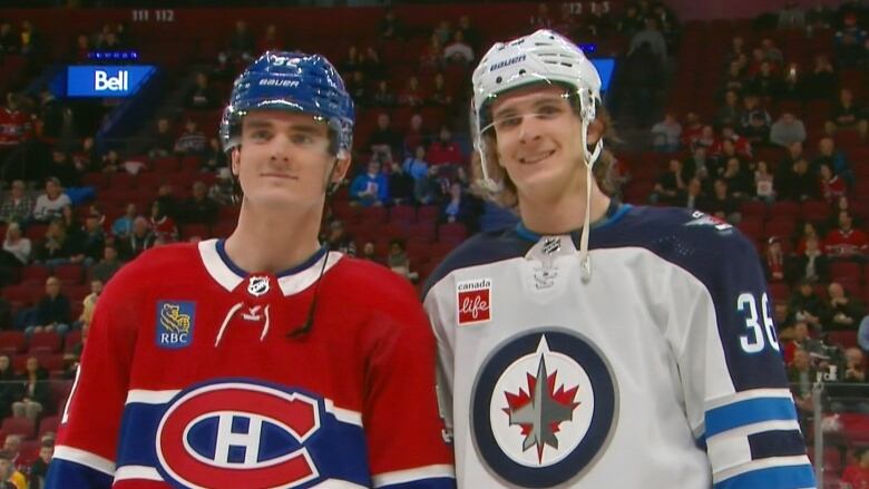 Two hockey players are standing together and smiling.