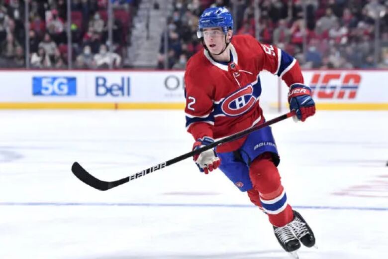 A hockey player wearing a Montreal Canadiens uniform is seen skating in a rink.