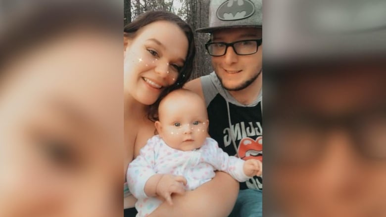 Two parents hold their baby in a selfie.