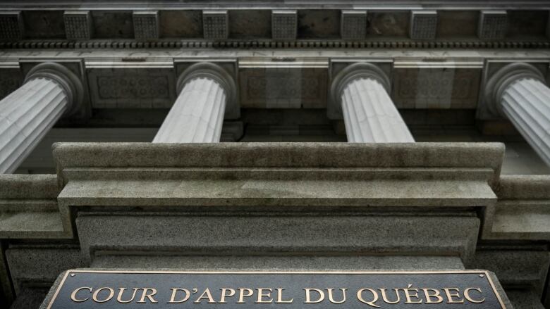 A view upward of a courthouse's pillars. Sign says Cour D'appel du Qubec.