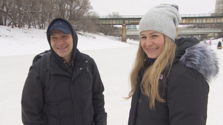 Two people in winter gear stand on the ice.