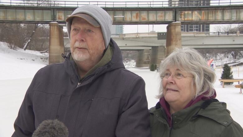 A married couple stand on the river trail.