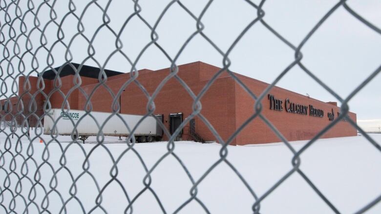 A large rectangular building made of red bricks stands in contrast to a blanket of white snow.