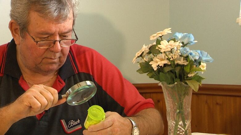 Pierre Filion uses a magnifying glass to read the label on his medication.