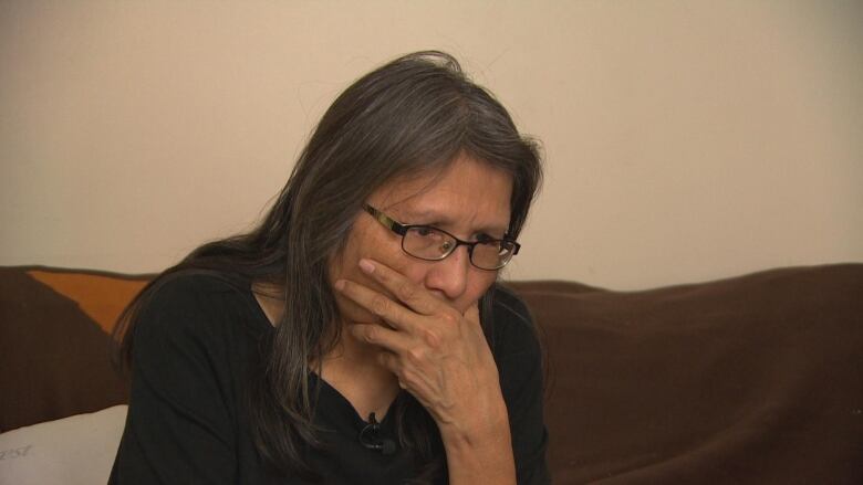  woman in a black shirt covers her mouth with her hand.