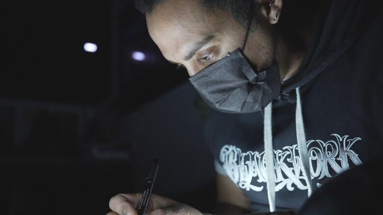 A man leans over a brightly lit work station.