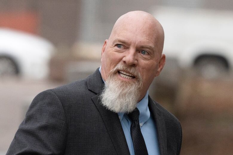 Bald man with grey beard in a suit