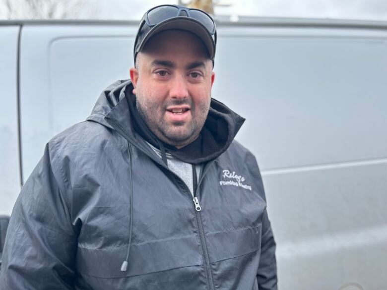 A man stands in front of a work van. 