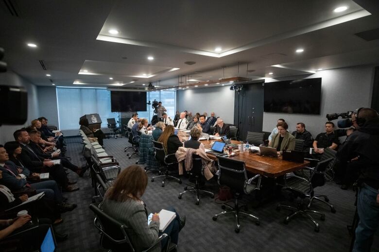 The 10 or so members of the Vancouver Police Board sit around a boardroom table as media and camera watch.