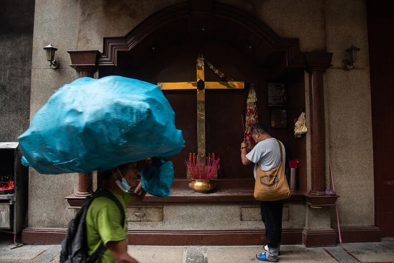 A man offers prayers in front of a niche on a street in Manila's Chinatown.