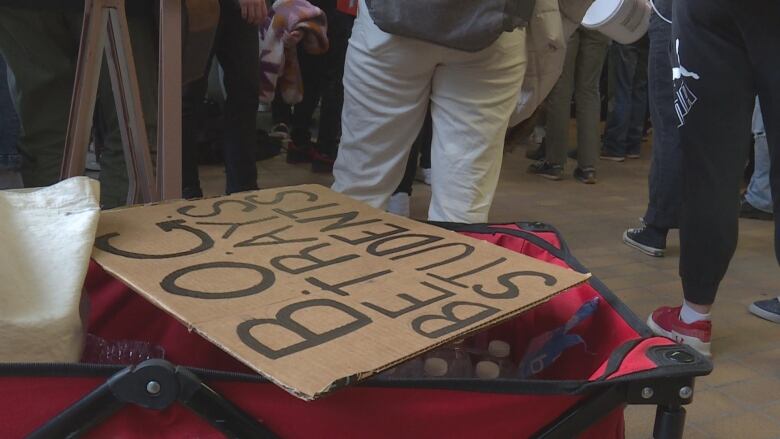 a sign over a wagon with people standing in the background. the sign reads b.o.g betrays students