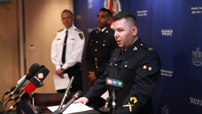 Leaders of the B.C. RCMP, the Vancouver Island Integrated Major Crimes Unit and the Saanich Police Department stand in uniform behind a podium to address media.