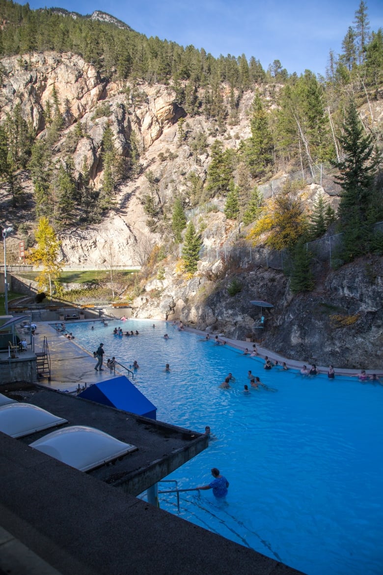 A blue pool cut into the side of a mountain is pictured in shadow.