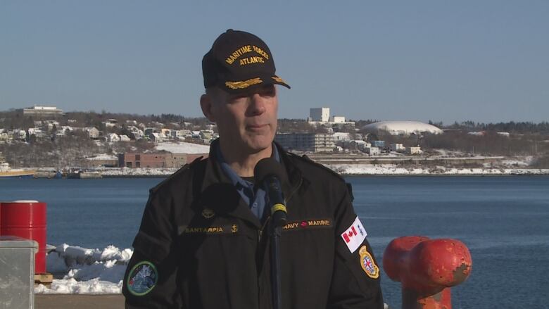 A man in a black Maritime Forces Atlantic cap speaks into a microphone.