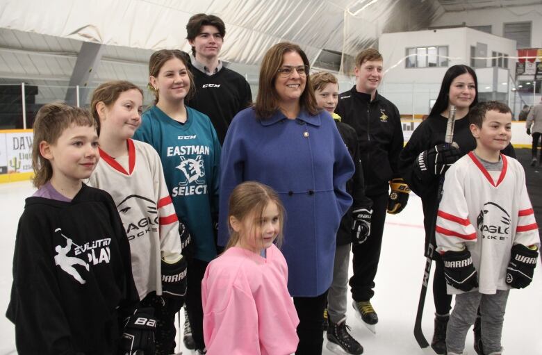 Manitoba Premier Heather Stefanson stands for a posed photo with some hockey players at the Lorette Community Complex.