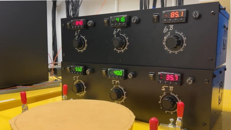 Different number readings are seen on a battery testing device that's a black box with six dials.