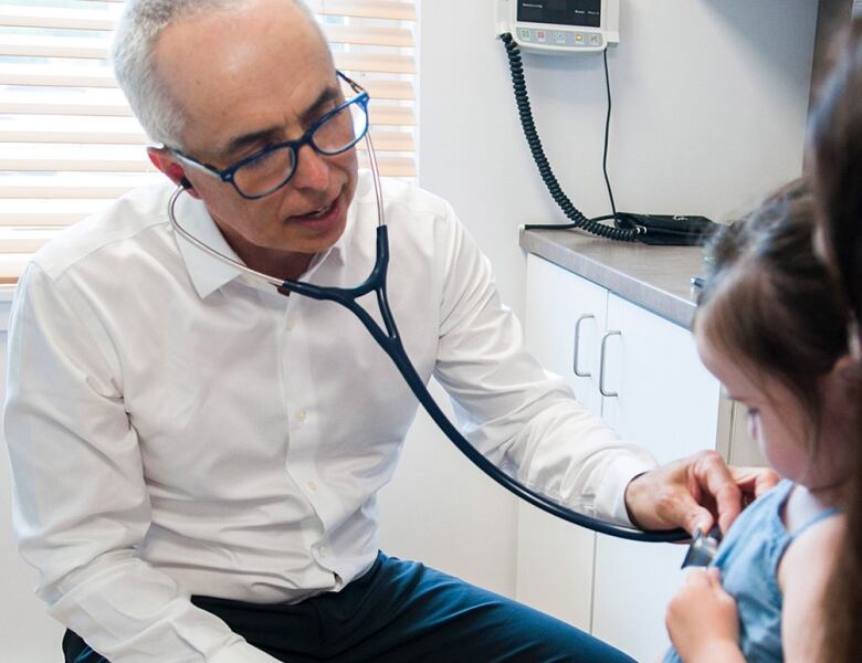 A man holding a stethoscope to a patient's chest.  