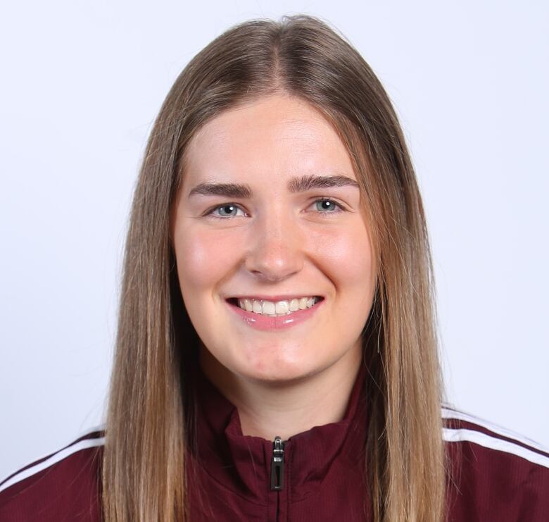 A woman with light brown hair, blue eyes and wearing a dark red SMU jacket smiles for a photo.