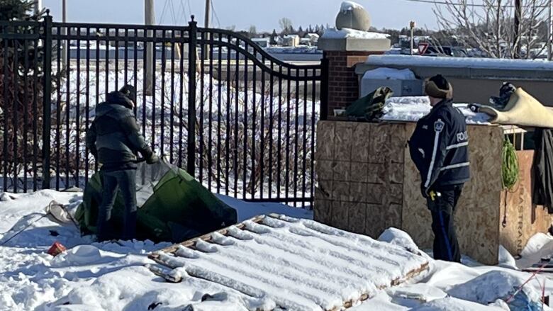 Police watch over as the encampment is dismantled.