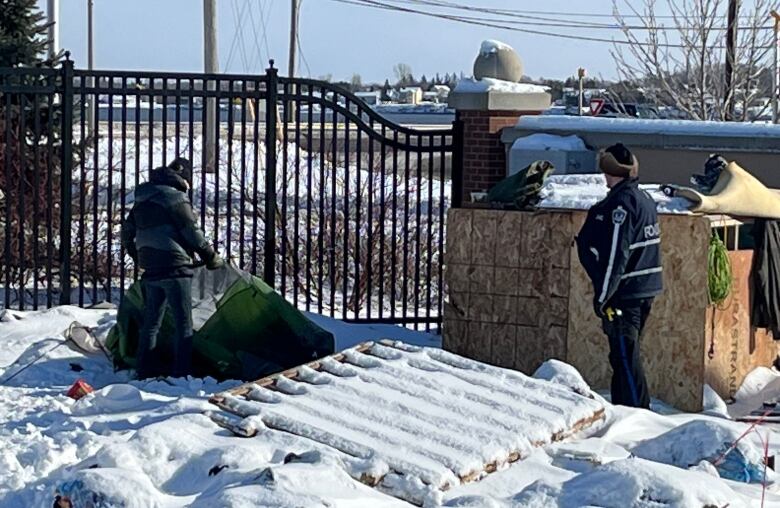 Police watch over as the encampment is dismantled.