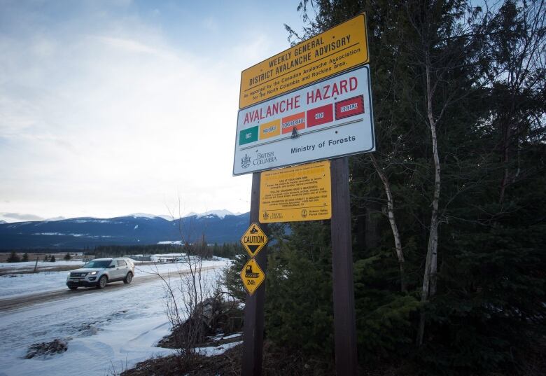 A vehicle passes a sign showing an avalanche hazard warning of 