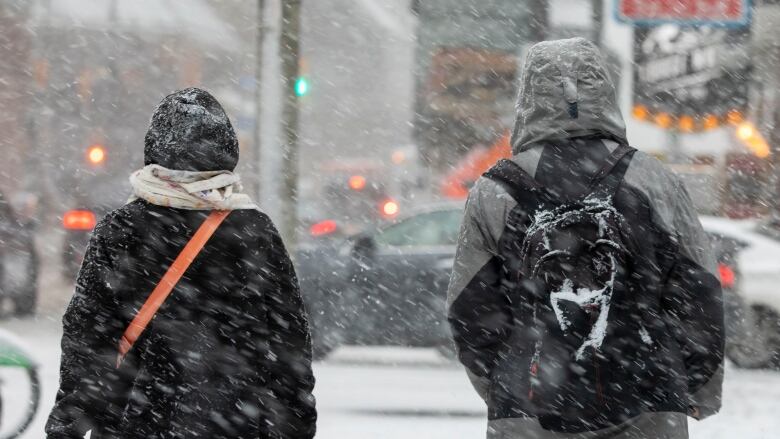 People walk down Front Street in downtown Toronto during the snowstorm on January 25, 2023.